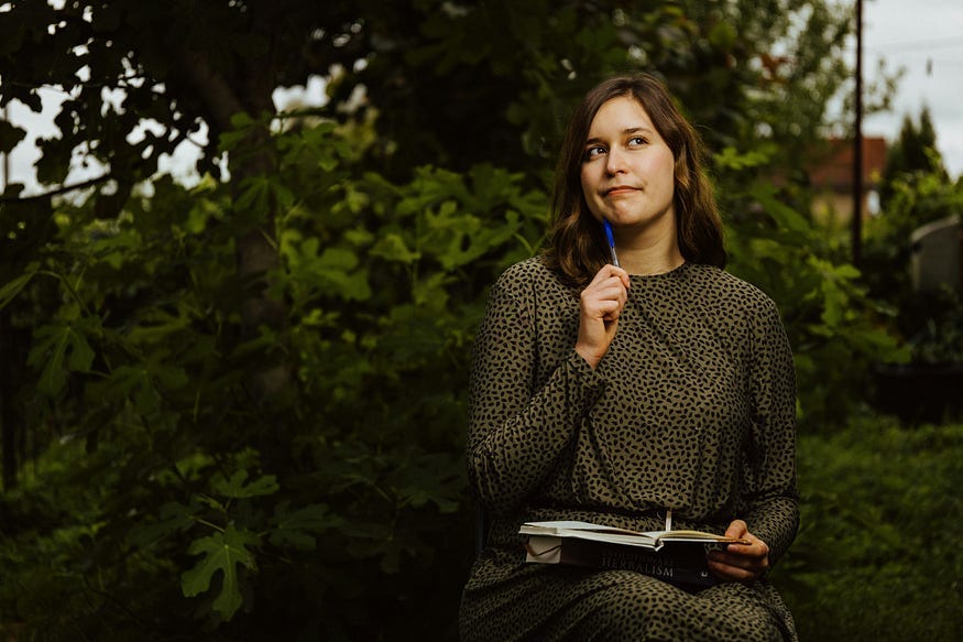 A woman sitting in the park and thinking as she writes A woman sitting in the park and thinking as she writes