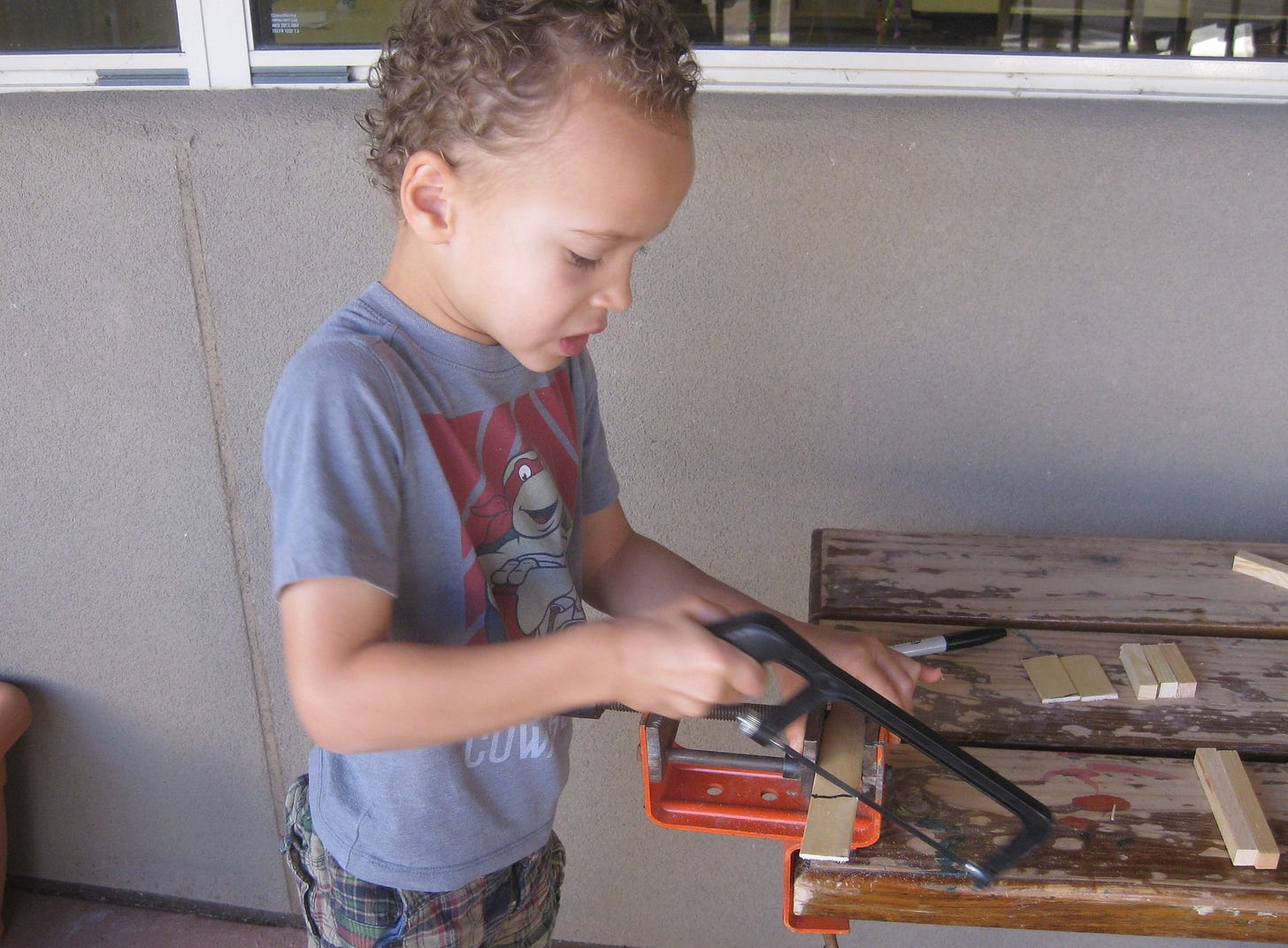 image of a boy cutting wood with a saw.