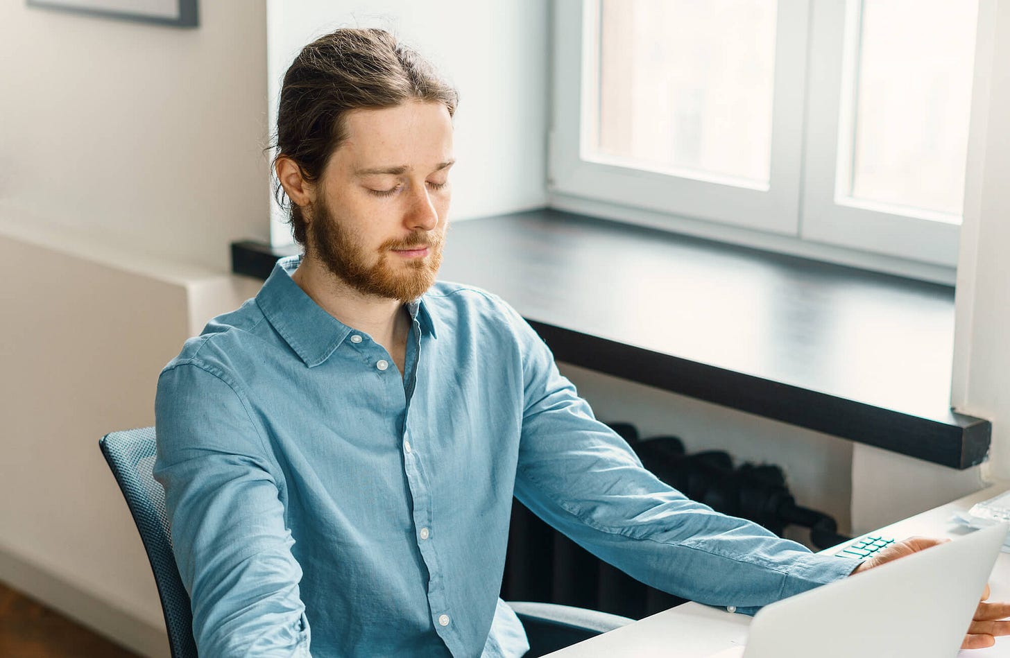A man meditating at his work desk