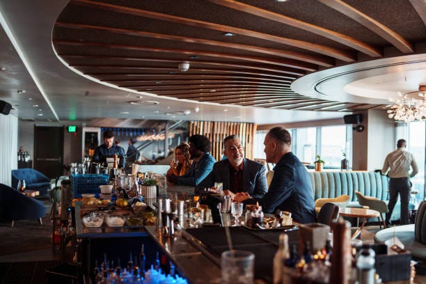 Patrons at the bar of an upscale restaurant A handsome man sits at the bar of an upscale restaurant and chats with his husband. bar and restaurant stock pictures, royalty-free photos & images