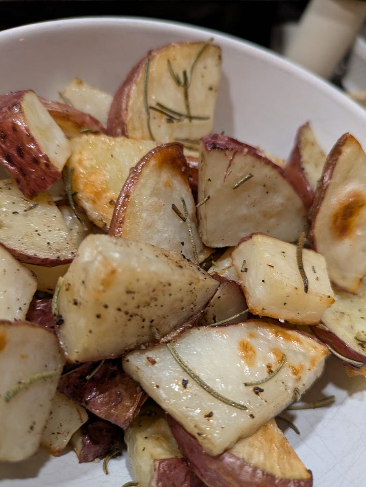 Bowl of braised beef and oxtail with vegetables. Roasted potatoes with rosemary.