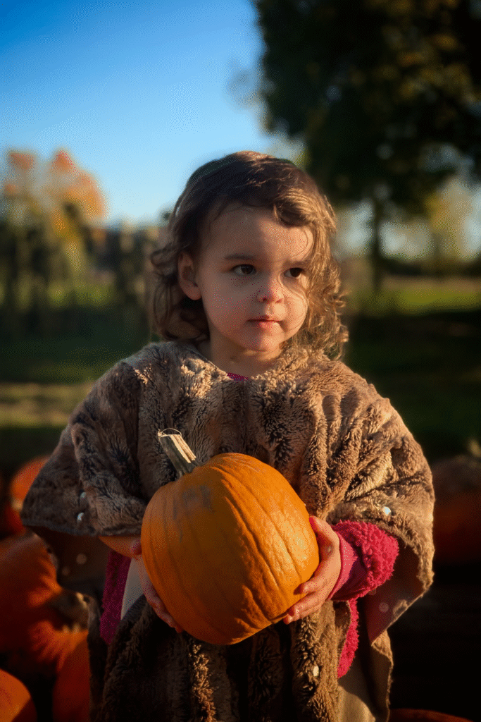 Canadian sovereignty and community resilience symbolized by a child holding a pumpkin at a farmers’ market in September.