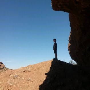 silhouette of a young man standing on the edge of a cliff (free to use images)