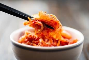 Cabbage kimchi in bowl with chopsticks