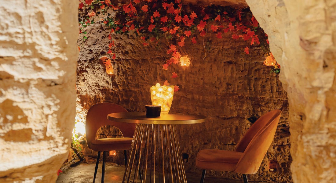 A table for two in the inside of a cave wall with autumn leaves above it A table for two in the inside of a cave wall with autumn leaves above it