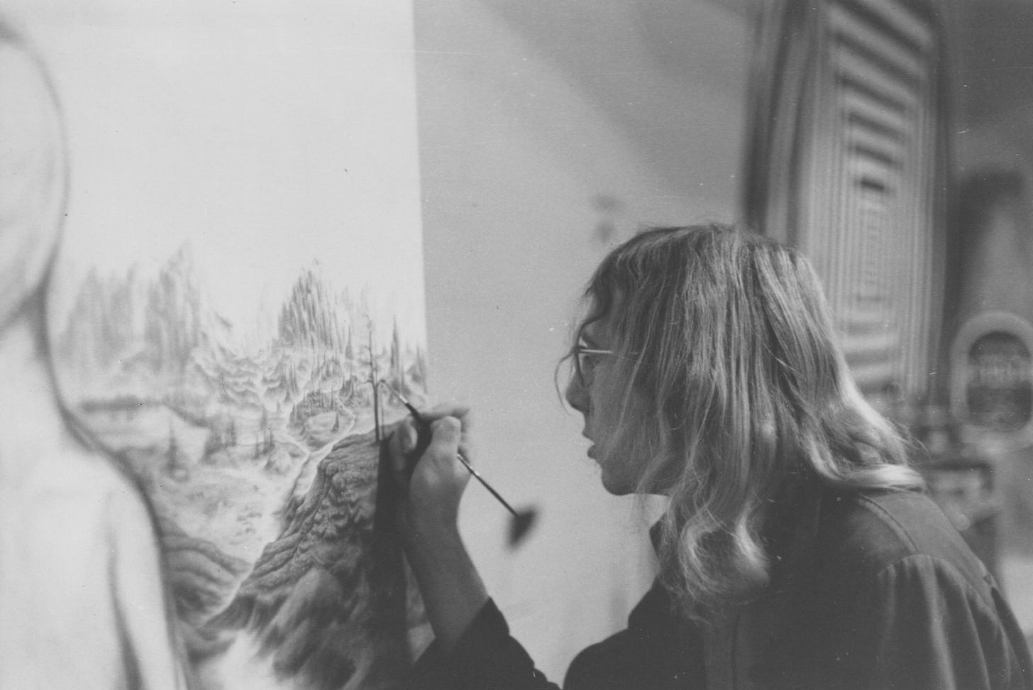 A young man with long hair painting on a large canvas.
