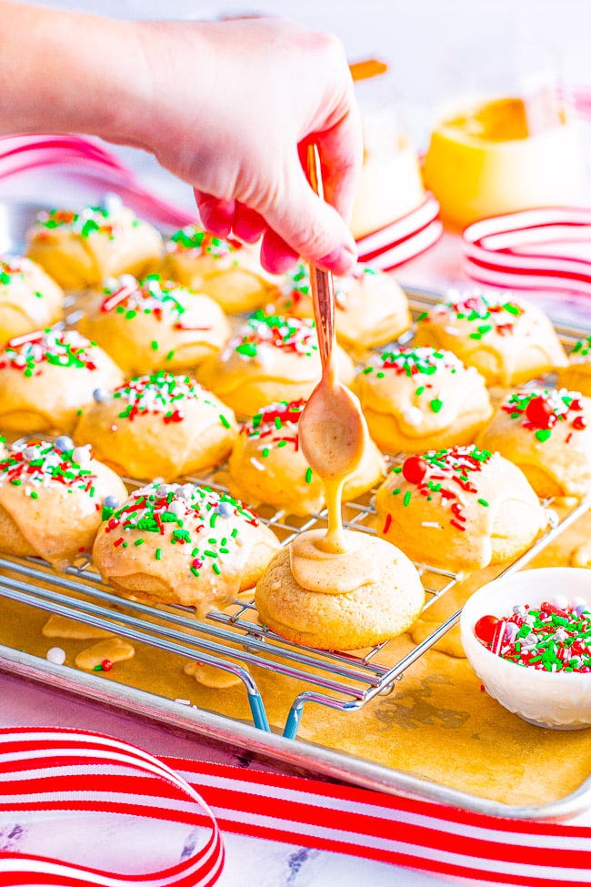 Eggnog Cookies on a wire rack being topped with eggnog glaze and sprinkles. Eggnog Cookies on a wire rack being topped with eggnog glaze and sprinkles.