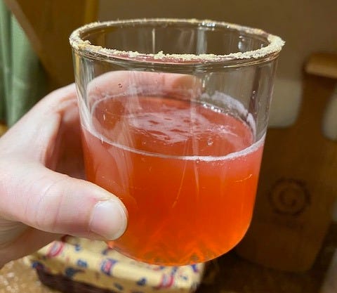hand holding an elderberry cocktail glass