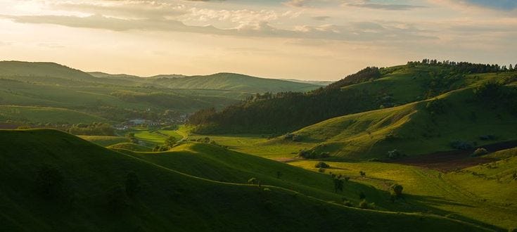 This may contain: the sun is shining on green hills and valleys