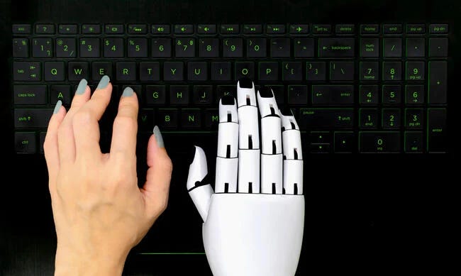 A human hand and a robot hand on a computer keyboard