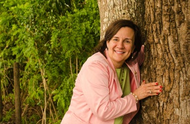 Attorney Vera Bergermann hugging a tree.