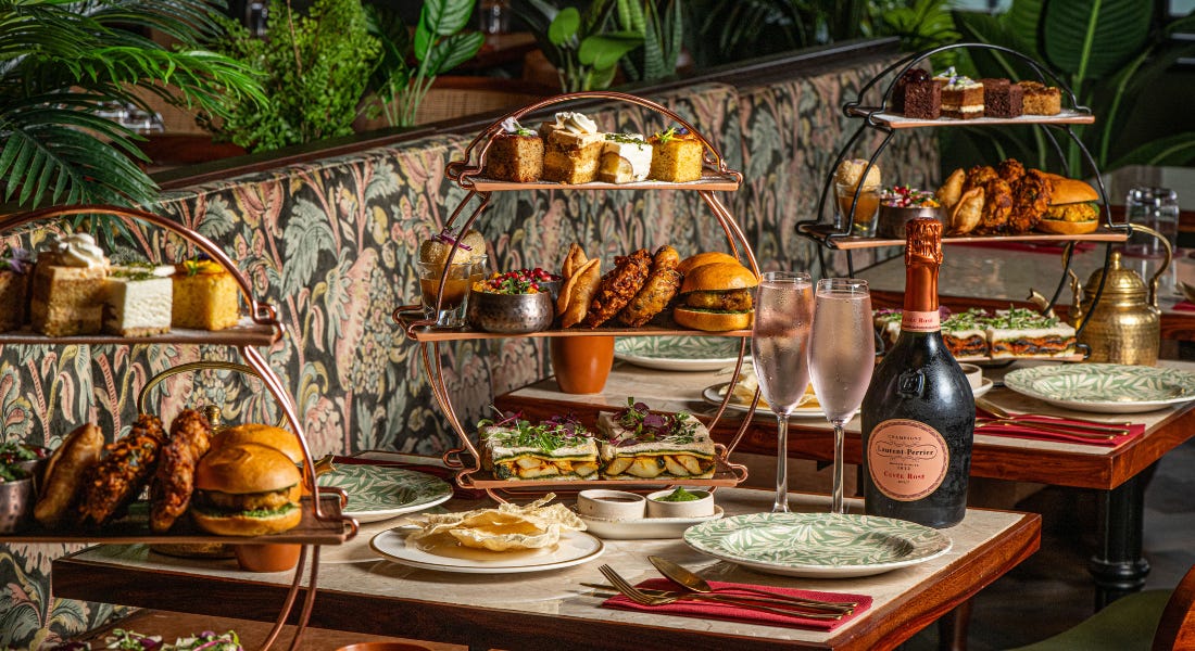 Three ornate tables with circular stands filled with Indian afternoon tea, placed against a floral background Three ornate tables with circular stands filled with Indian afternoon tea, placed against a floral background