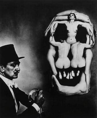 A black-and-white photograph of Salvador Dali in profile next to several nude women posed in the shape of a skull.