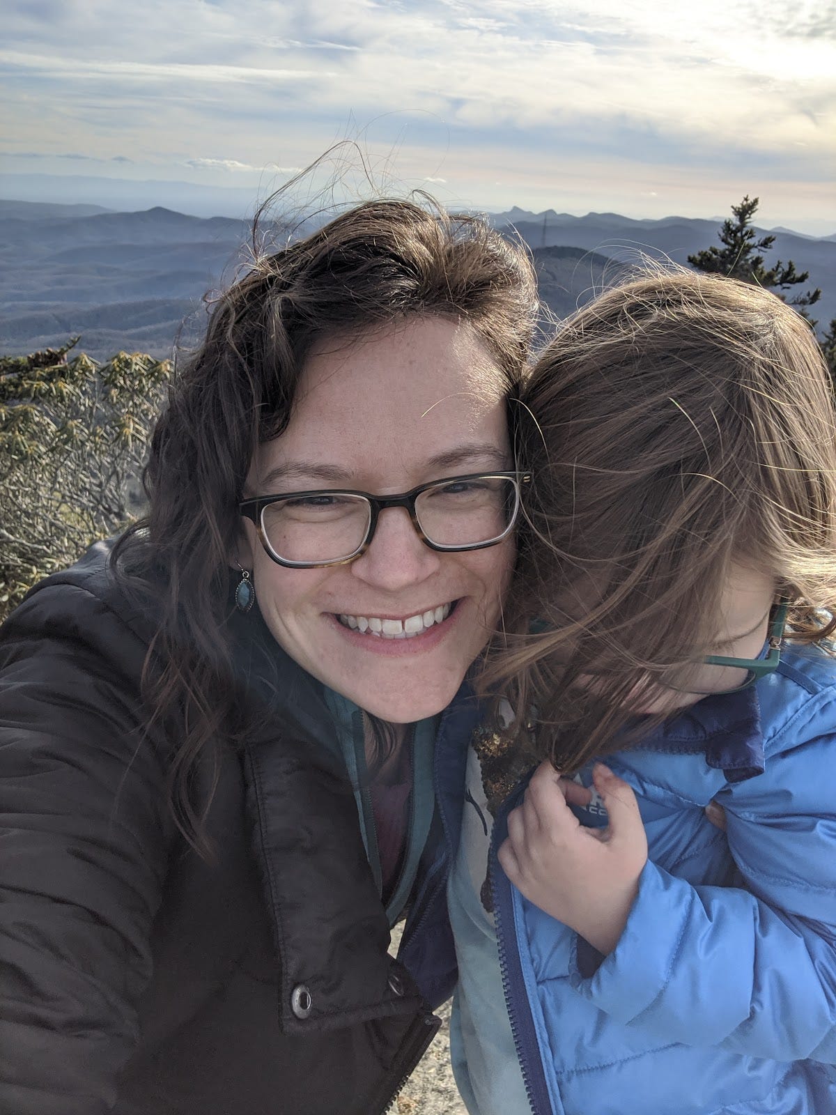 Shannon hugging her daughter, who is looking down, with mountains in the background