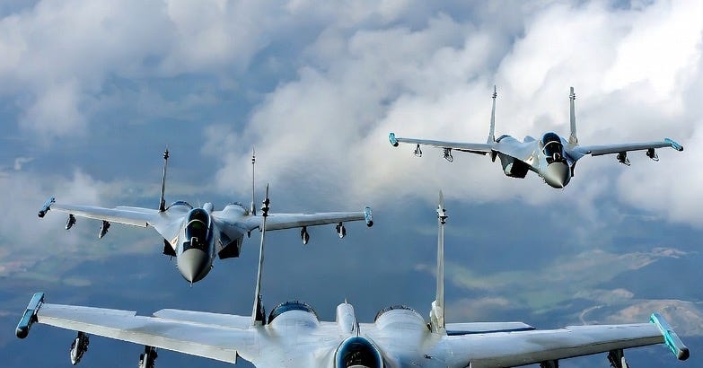 Three SU-57 fighter jets in formation over a natural landscape during daytime.