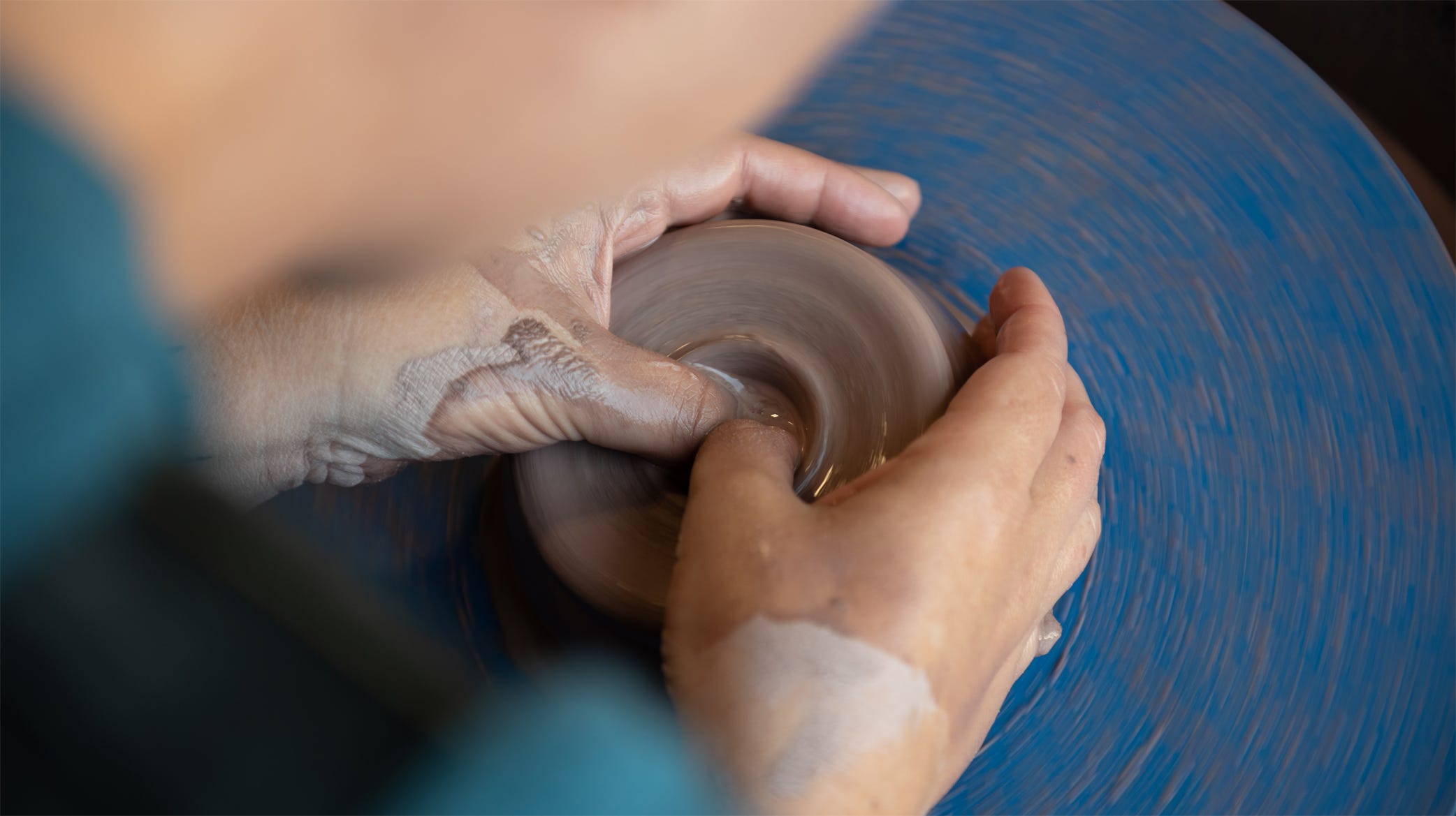 Potter making a teapot on the wheel.