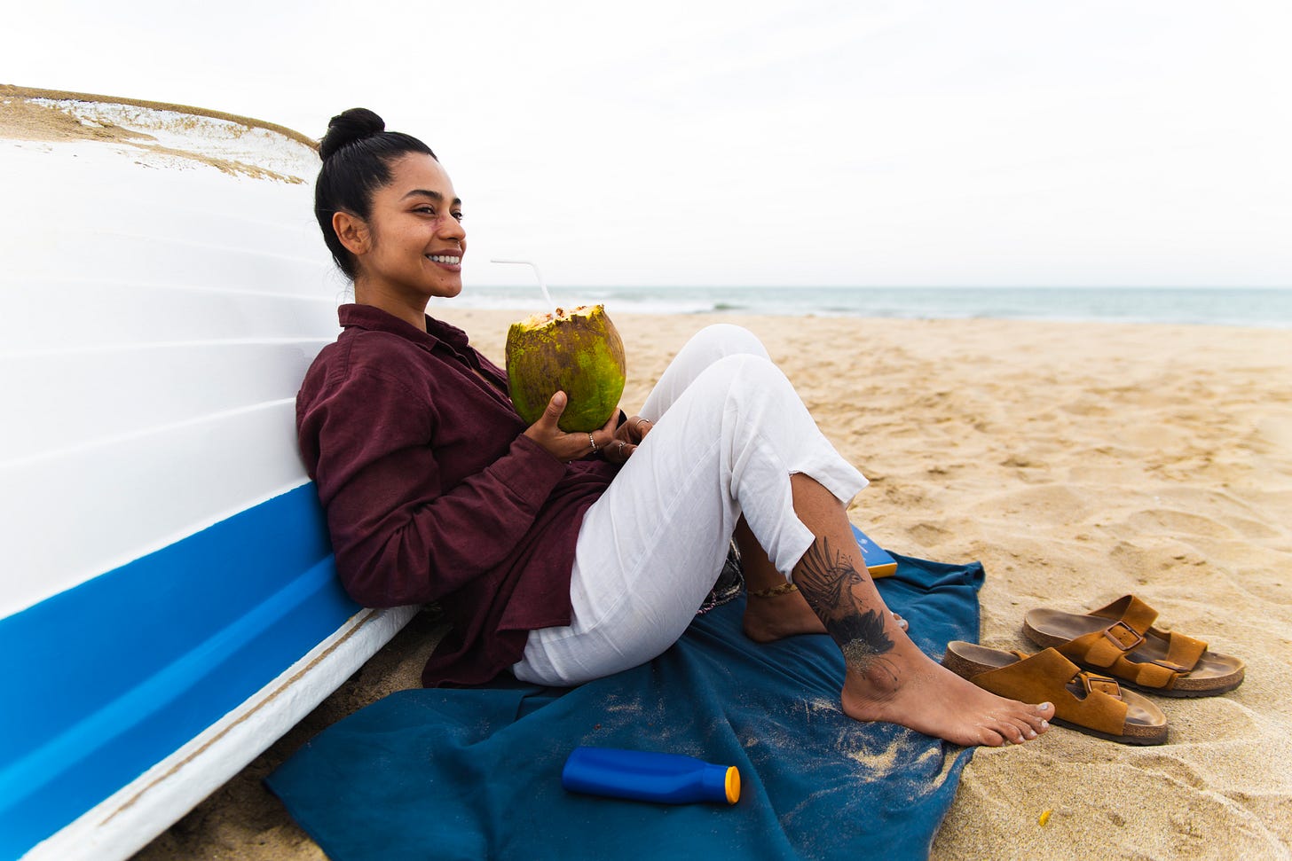Woman drinking coconut water out of a coconut on the beach Woman drinking coconut water out of a coconut on the beach