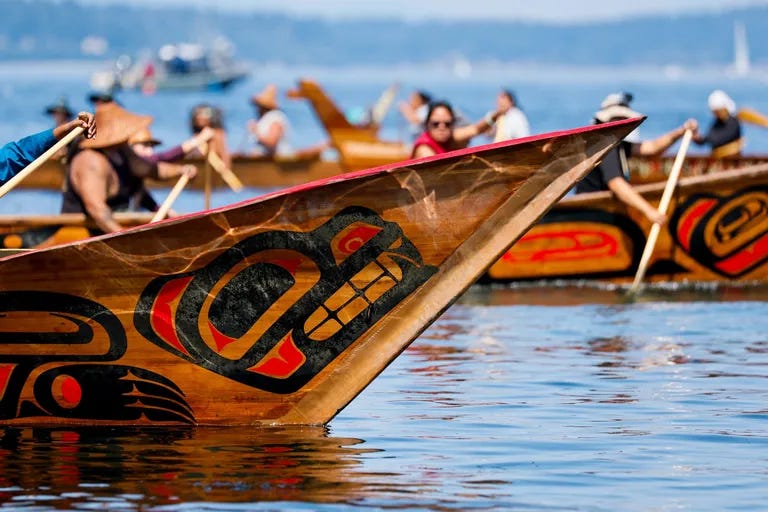 Intricate paintings adorn canoes waiting to come ashore at Alki on Sunday. (Jennifer Buchanan / The Seattle Times)