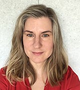 Sue Peters wearing a red top, smiling slightly against a plain light background. Sue Peters wearing a red top, smiling slightly against a plain light background.