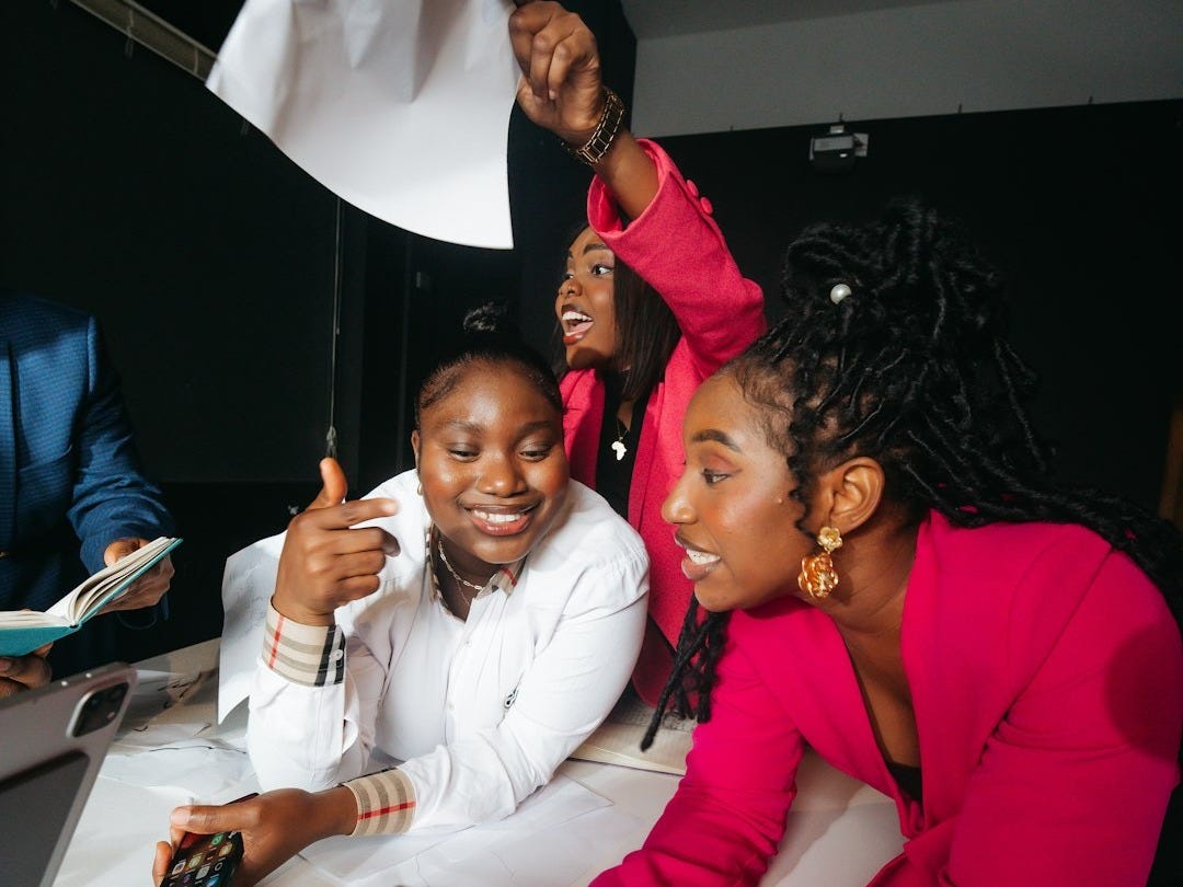 Three women celebrating and holding a white flag.