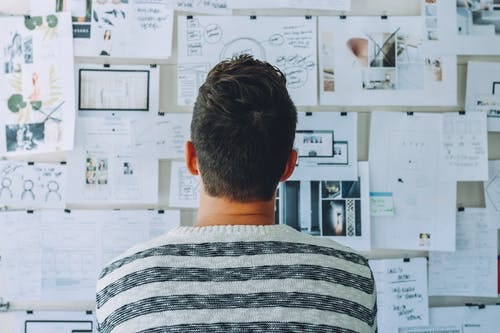 Man Wearing Black and White Stripe Shirt Looking at White Printer Papers on the Wall Man Wearing Black and White Stripe Shirt Looking at White Printer Papers on the Wall