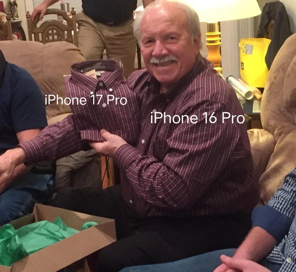 An older man with a mustache wearing a red and white striped shirt sits on a couch, holding a folded shirt in front of him. Text overlays on the image read "iPhone 17,Pro" on the upper part of the folded shirt and "iPhone 16,Pro" on the lower part. Other people are partially visible around him, sitting on furniture in a living room setting with a lamp and green tissue paper from a box nearby. An older man with a mustache wearing a red and white striped shirt sits on a couch, holding a folded shirt in front of him. Text overlays on the image read "iPhone 17,Pro" on the upper part of the folded shirt and "iPhone 16,Pro" on the lower part. Other people are partially visible around him, sitting on furniture in a living room setting with a lamp and green tissue paper from a box nearby.