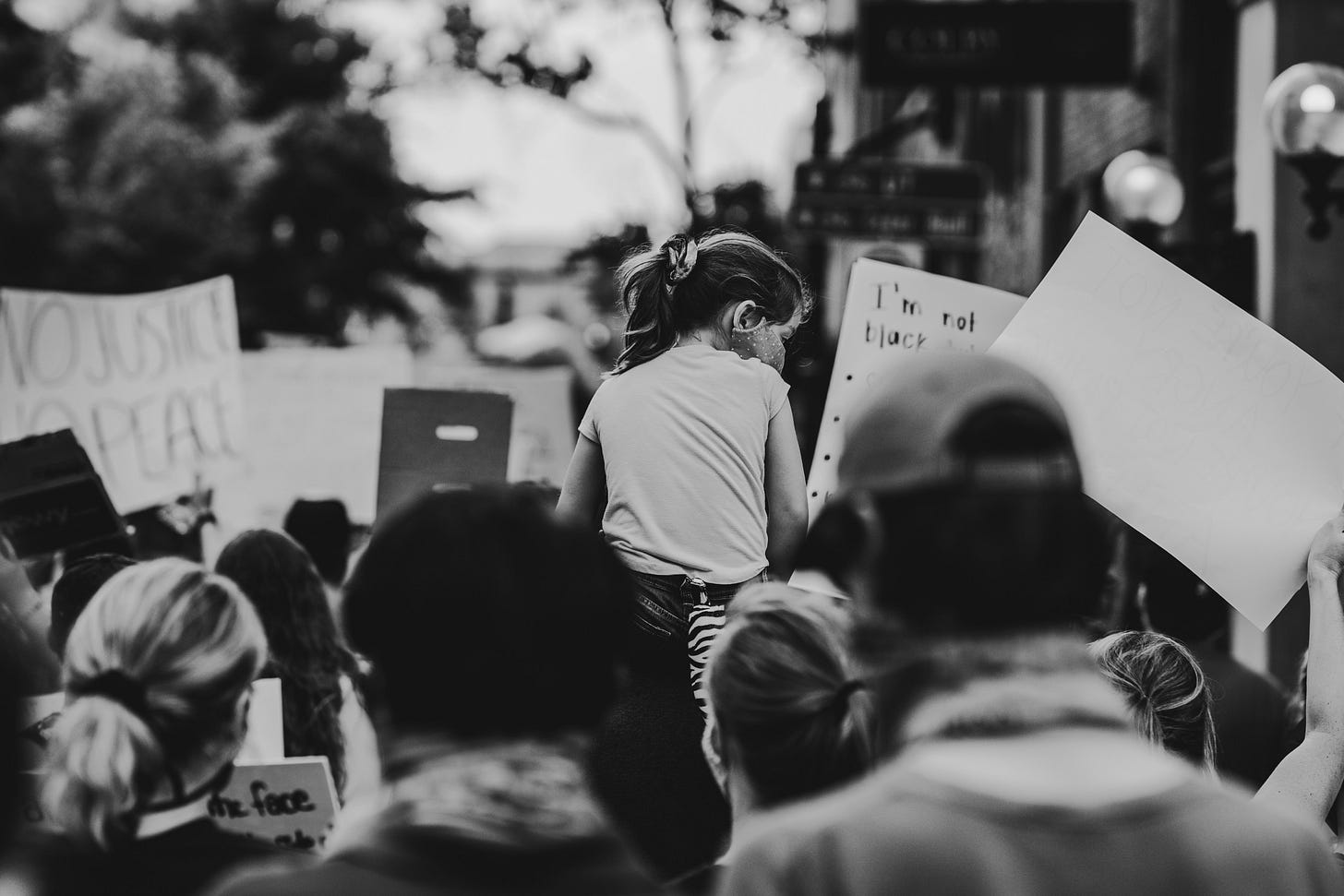 Black and white photo of a Black Lives Matter protest in Tennessee. The perspective is from the back of a crowd and there are a couple of homemade signs in the foreground.