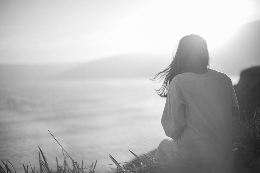 woman wearing gray long-sleeved shirt facing the sea woman wearing gray long-sleeved shirt facing the sea