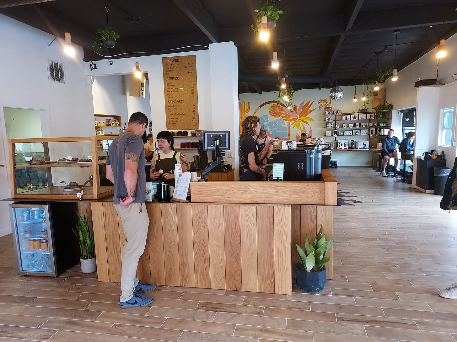 A gentleman orders coffee from a barista in a bright coffee shop. A gentleman orders coffee from a barista in a bright coffee shop.