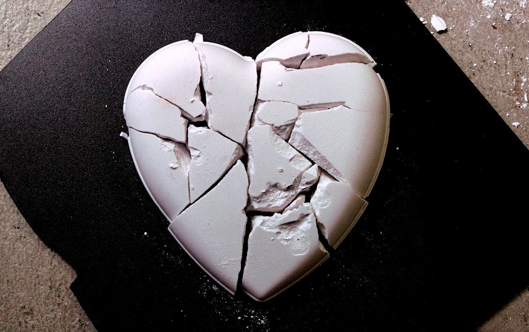 A broken heart shaped cookie sitting on top of a table A broken heart shaped cookie sitting on top of a table
