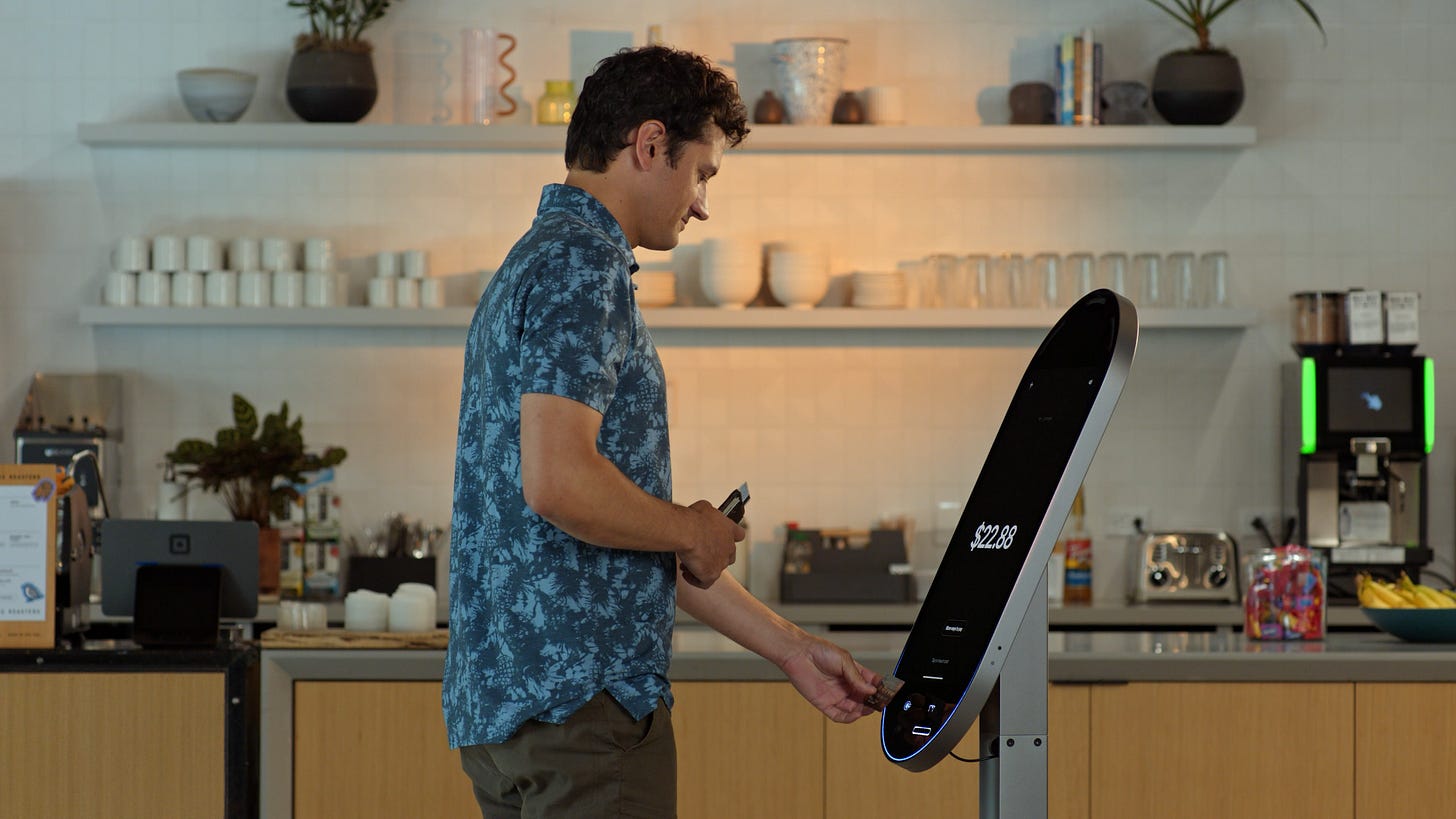 A man uses a Square's new kiosk, a long oval with a 21.5-inch screen. A man uses a Square's new kiosk, a long oval with a 21.5-inch screen.