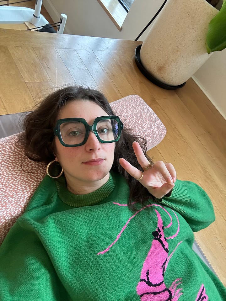 phoebe laying down on her couch. She has brown hair and big glasses