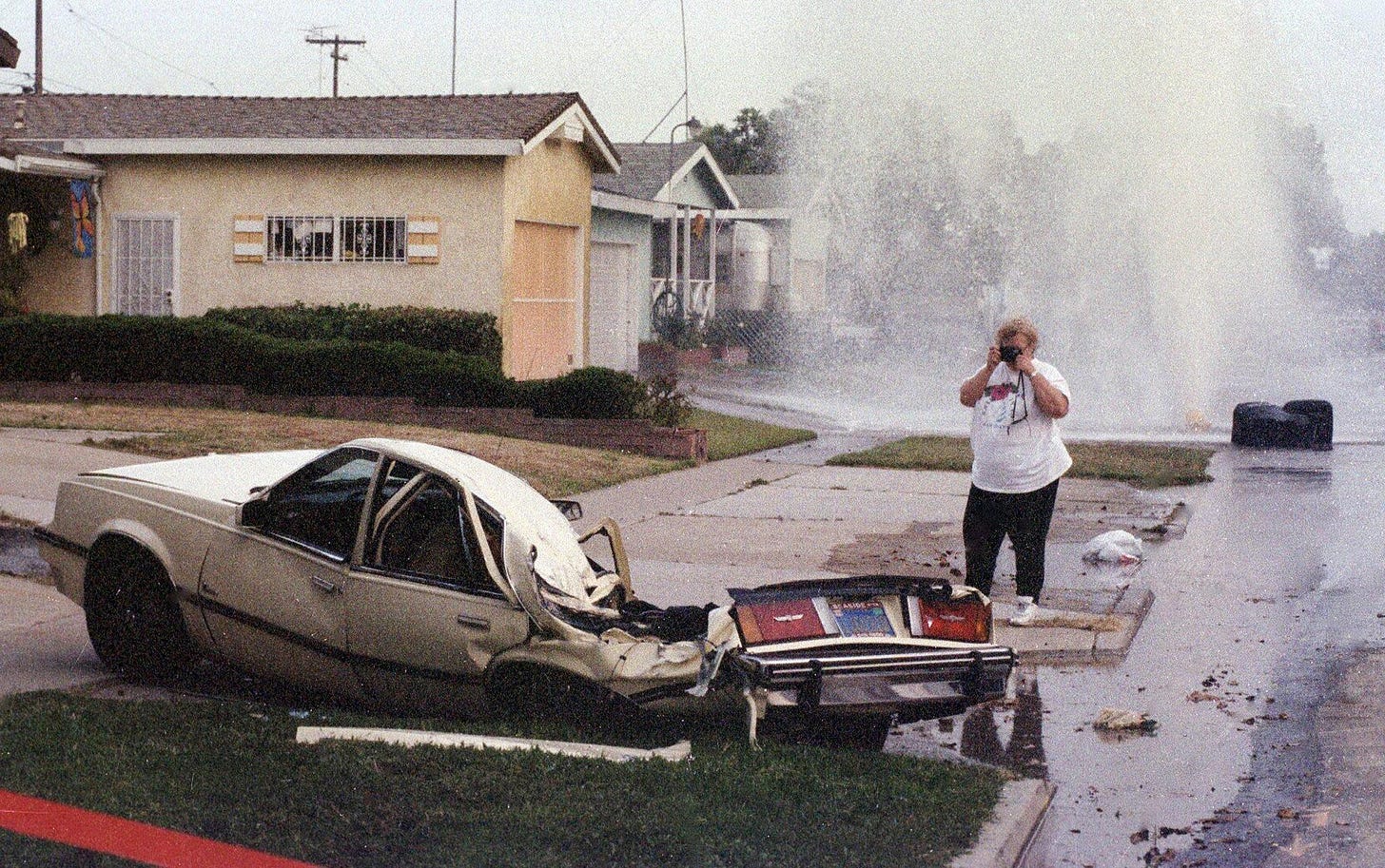 A woman photographs a car utterly destroyed after Shawn Nelson's infamous tank rampage, May 17, 1995. Photo by Eduardo Contreras.