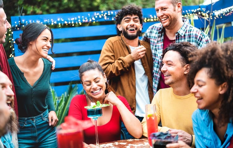 A group of young adults having drinks and socialising. A group of young adults having drinks and socialising.