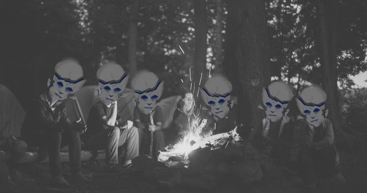 Masked figures sitting around a campfire in the woods at night. A woman in the middle of the group is the only one without a mask.