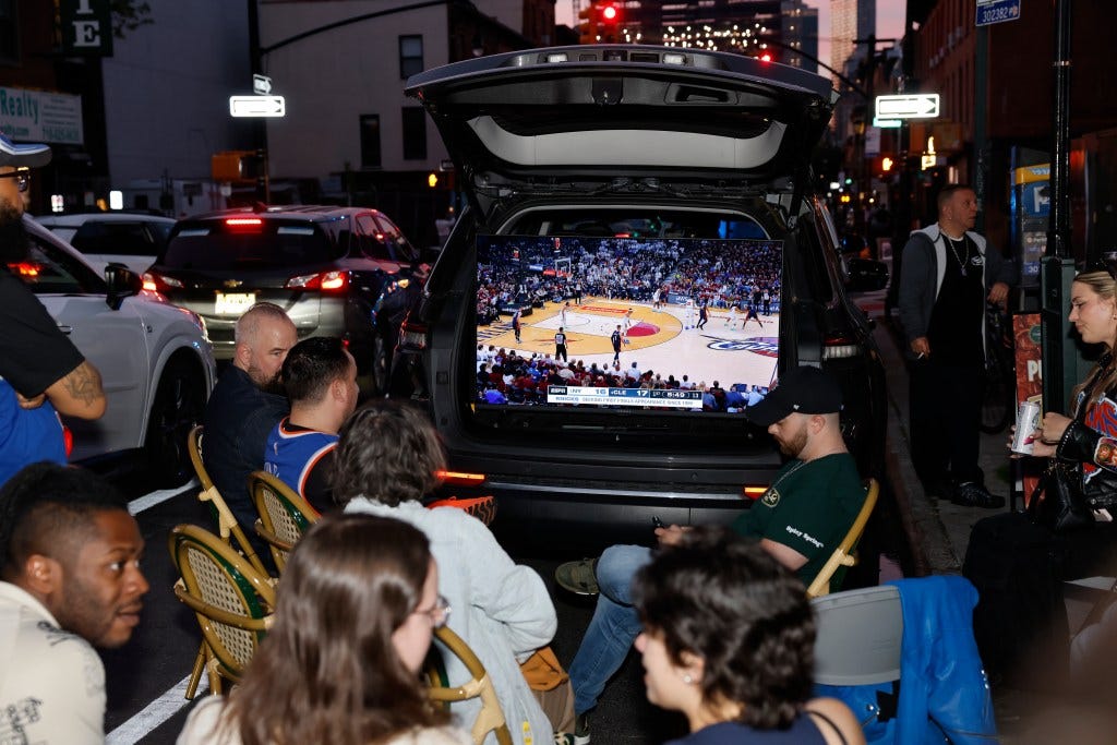 Dominic Morano, 33, whose family owns Prince Street Pizzeria, stands beside a 50-inch television set up in the trunk of his 2024 Jeep Grand Cherokee