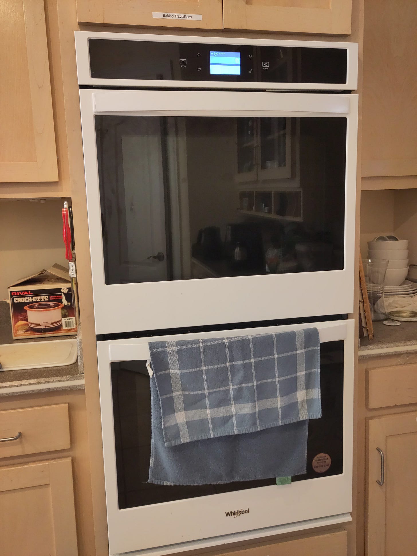 A double oven in a kitchen with a small touch screen on top.