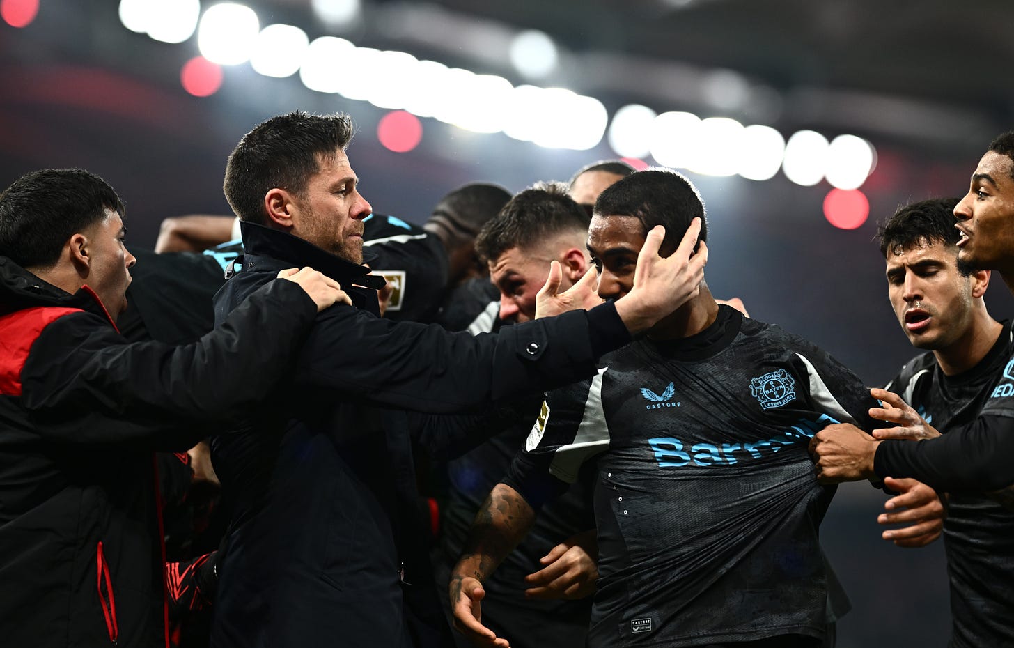 Bayer Leverkusen manager Xabi Alonso holds Arthur's head in the middle of a player huddle.
