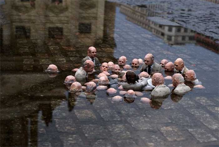 A statue of men in suits talking, with water rising around them A statue of men in suits talking, with water rising around them