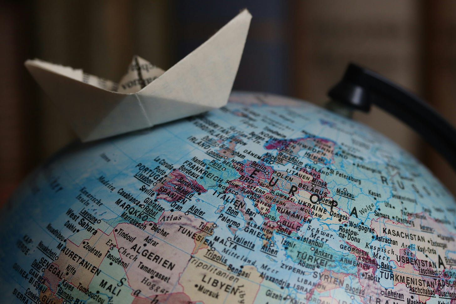 A paper boat resting on top of a globe, symbolizing how small creations can travel widely and make a broad impact.