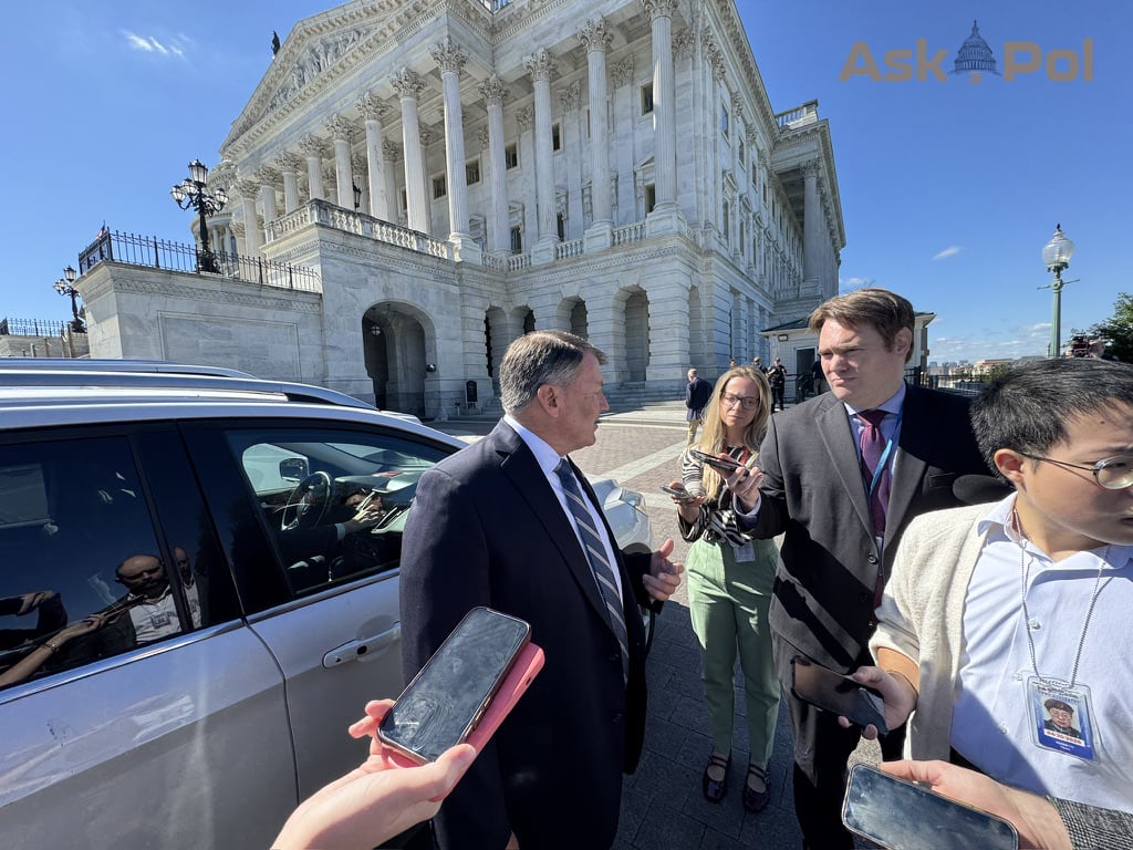 A Senator in a suit answers reporter's questions on sunny day outside large marble US Capitol. Photo: Matt Laslo © www.askapol.com