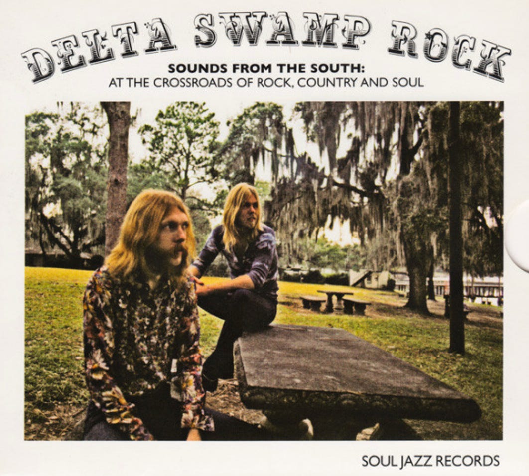 cover of Delta Swamp Rock, with two hippie looking rangy long hairs sitting at a picnic table in front of a trees