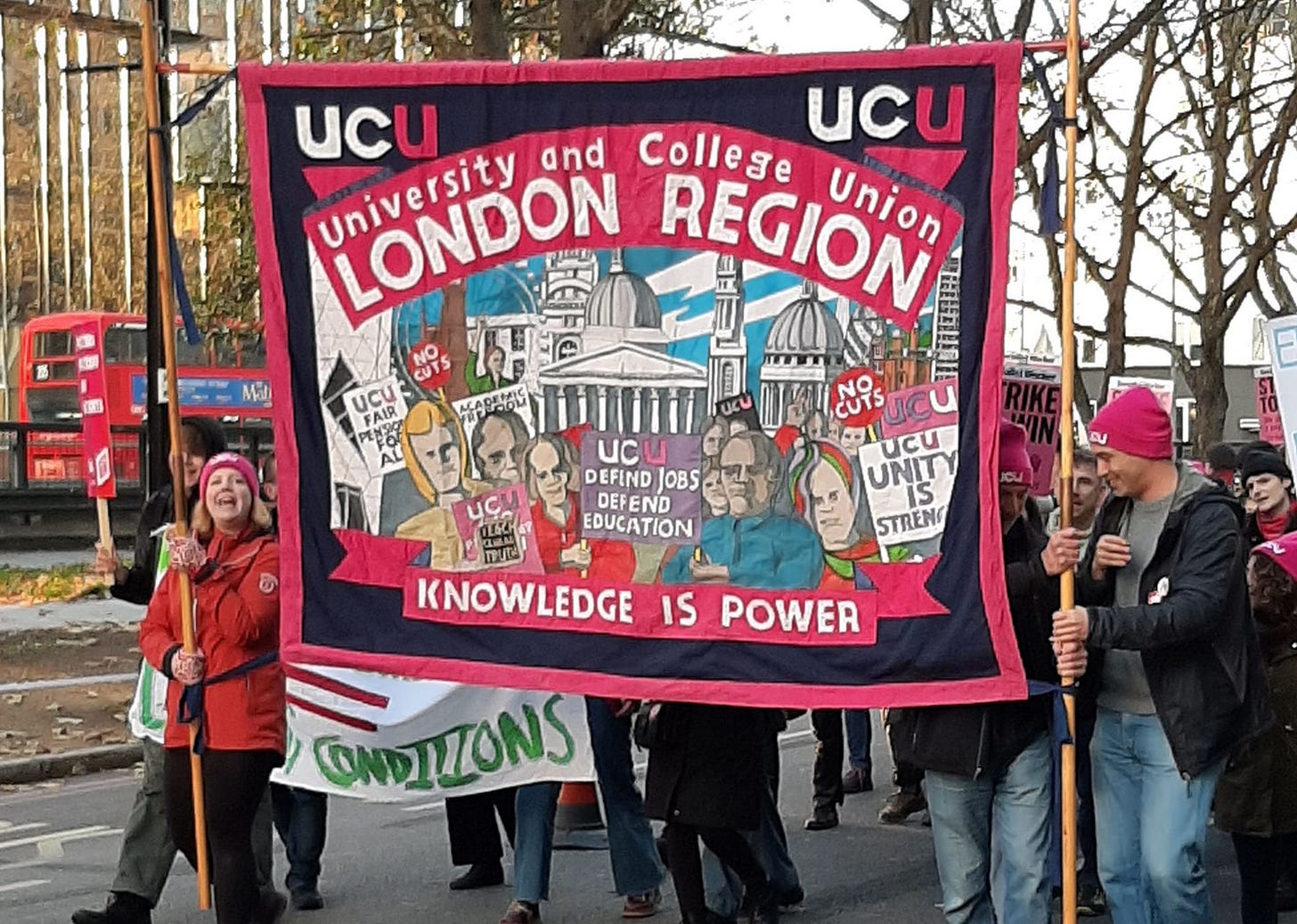 People march holding a banner through Fitzrovia. The banner reads: Knowledge is Power. University and College Union, London Region.