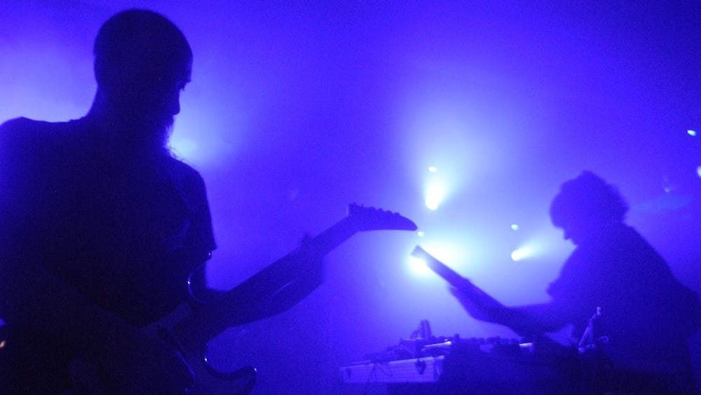 Two people playing guitars in a concert setting