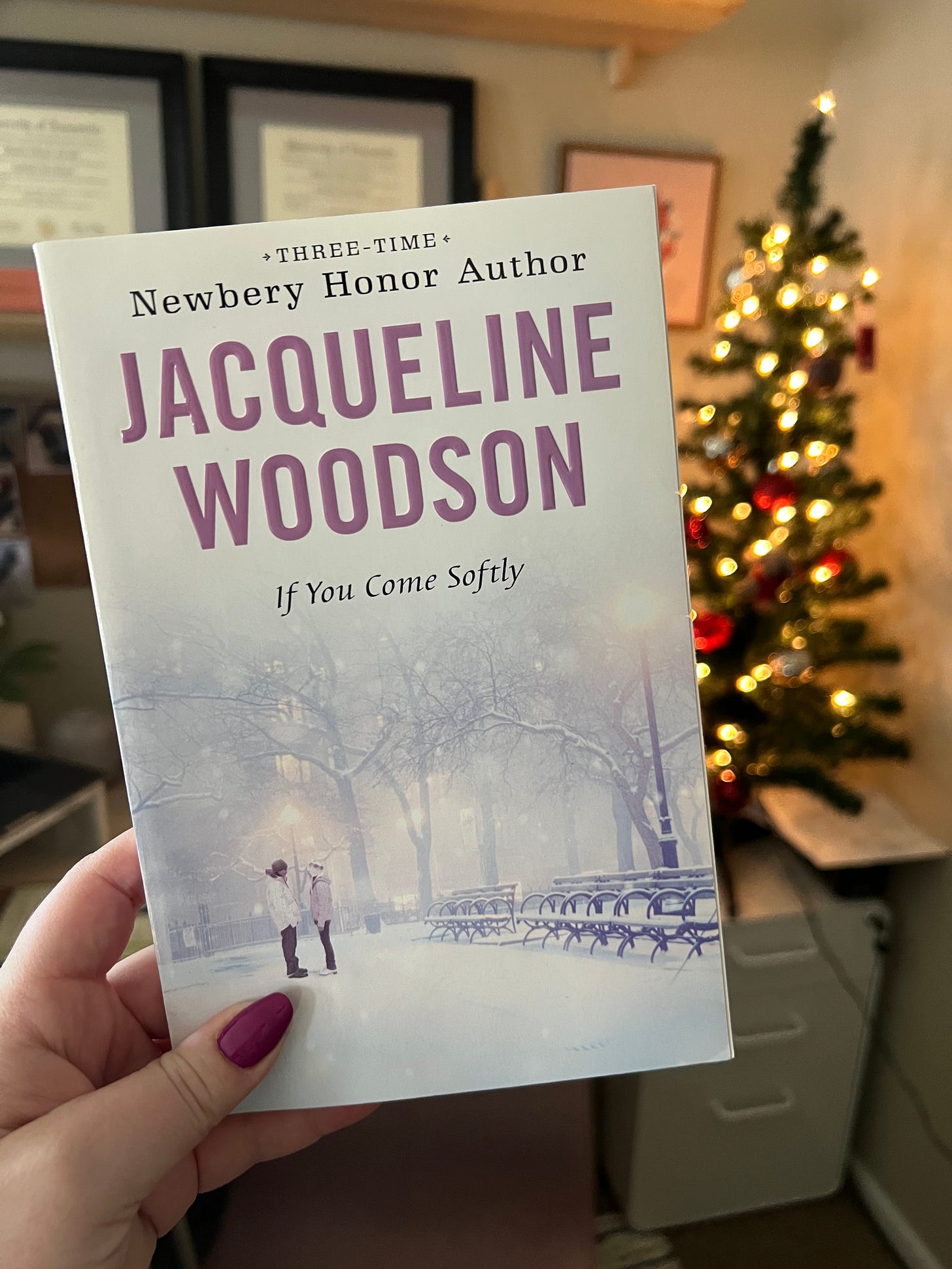 My hand holding up a paperback copy of If You Come Softly