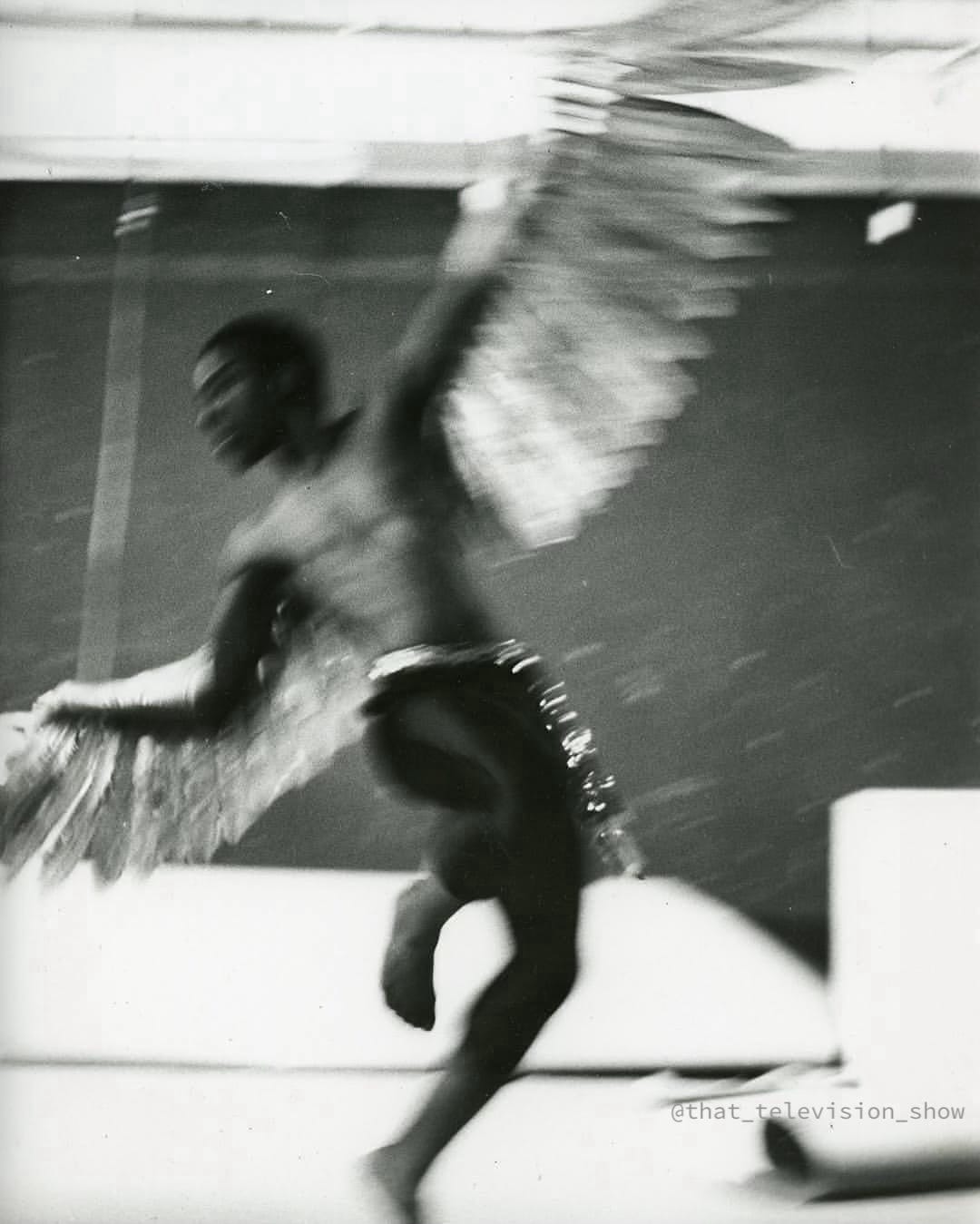 black and white photograph of a Black man with wings caught midway through a dance so that his image is blurred and his expression unreadable