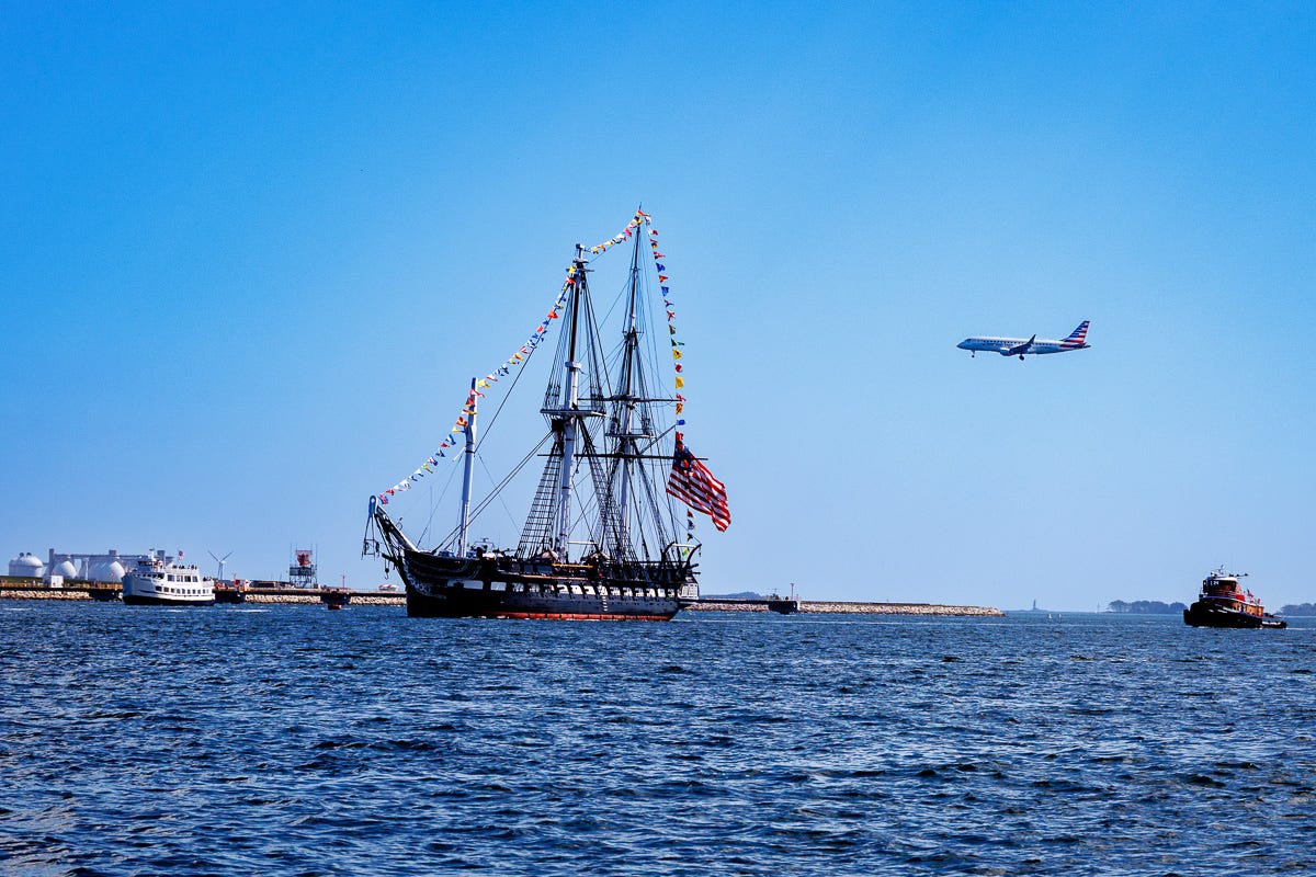 USS Constitution sailing past Logan Airport with airplane overhead USS Constitution sailing past Logan Airport with airplane overhead