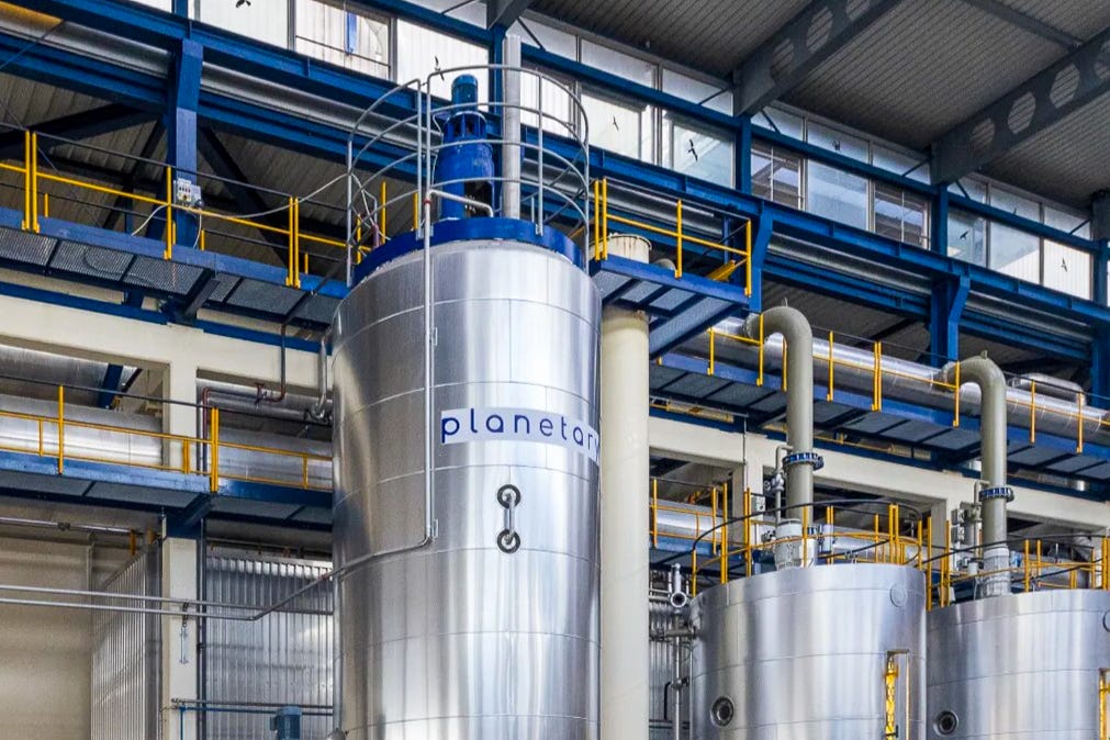 Grosse, silbrig glänzende Fermentations-Tanks mit dem blauen Schriftzug „planetary“ stehen in einer modernen Industriehalle der Zuckerfabrik in Aarberg; gelbe Geländer und blau lackierte Stahlträger umgeben die mehrstöckige Anlage. Grosse, silbrig glänzende Fermentations-Tanks mit dem blauen Schriftzug „planetary“ stehen in einer modernen Industriehalle der Zuckerfabrik in Aarberg; gelbe Geländer und blau lackierte Stahlträger umgeben die mehrstöckige Anlage.