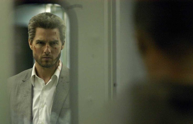 This may contain: a man looking at himself in the mirror while he is wearing a suit and tie