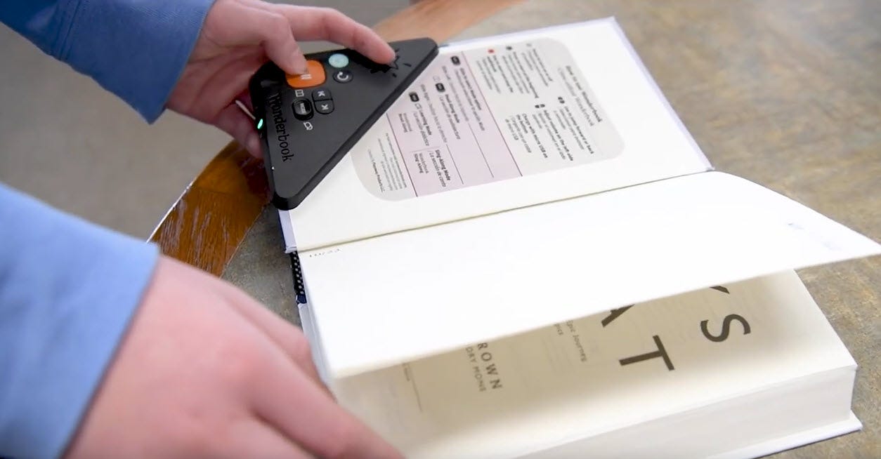 A person using a Wonderbook device to read the book aloud to them while they hold it A person using a Wonderbook device to read the book aloud to them while they hold it